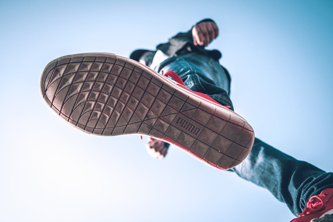 features-03 Low angle view of person wearing sneakers with focus on the sole against blue sky.