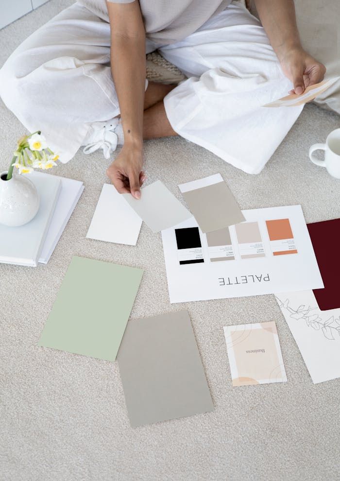 Mastering the First Impression: Your intriguing post title goes here Designer sits on carpet with color palettes and samples, planning creative project.